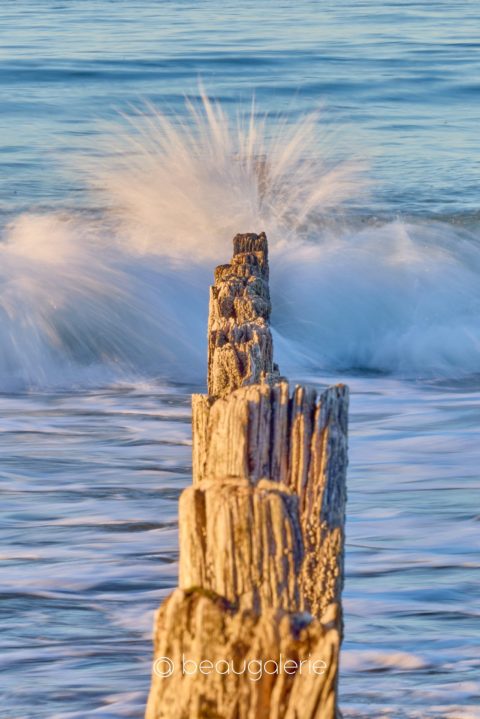 Vagues éclatant sur des brise-lames en bois à Saint-Malo au coucher du soleil