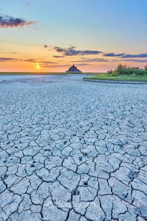 Sol craquelé devant le Mont Saint-Michel au coucher du soleil