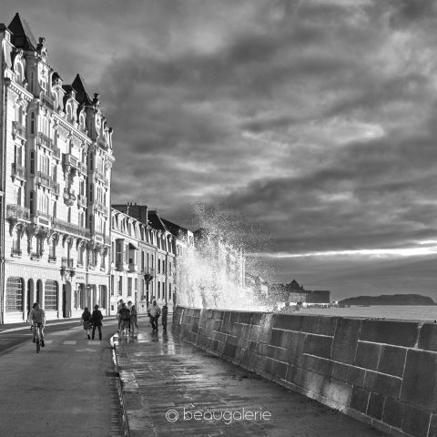 Vague éclaboussant la digue à Saint-Malo en noir et blanc