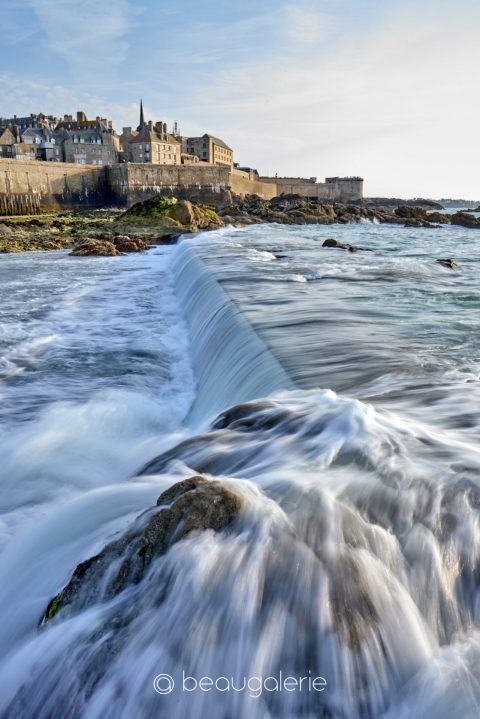 Photo en pose lente de la plage de l’Éventail à Saint-Malo, avec remparts en arrière-plan et mer fluide
