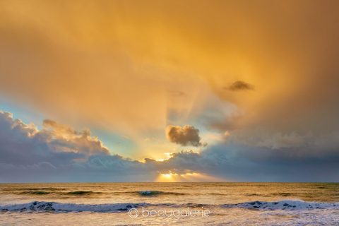 Rayons or baie Audierne perçant les nuages au coucher du soleil sur l'océan à Plozévet.