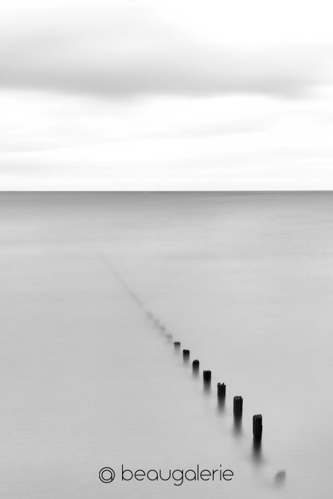 Photographie minimaliste brise-lames Saint-Malo en noir et blanc pose longue sur la plage du Sillon