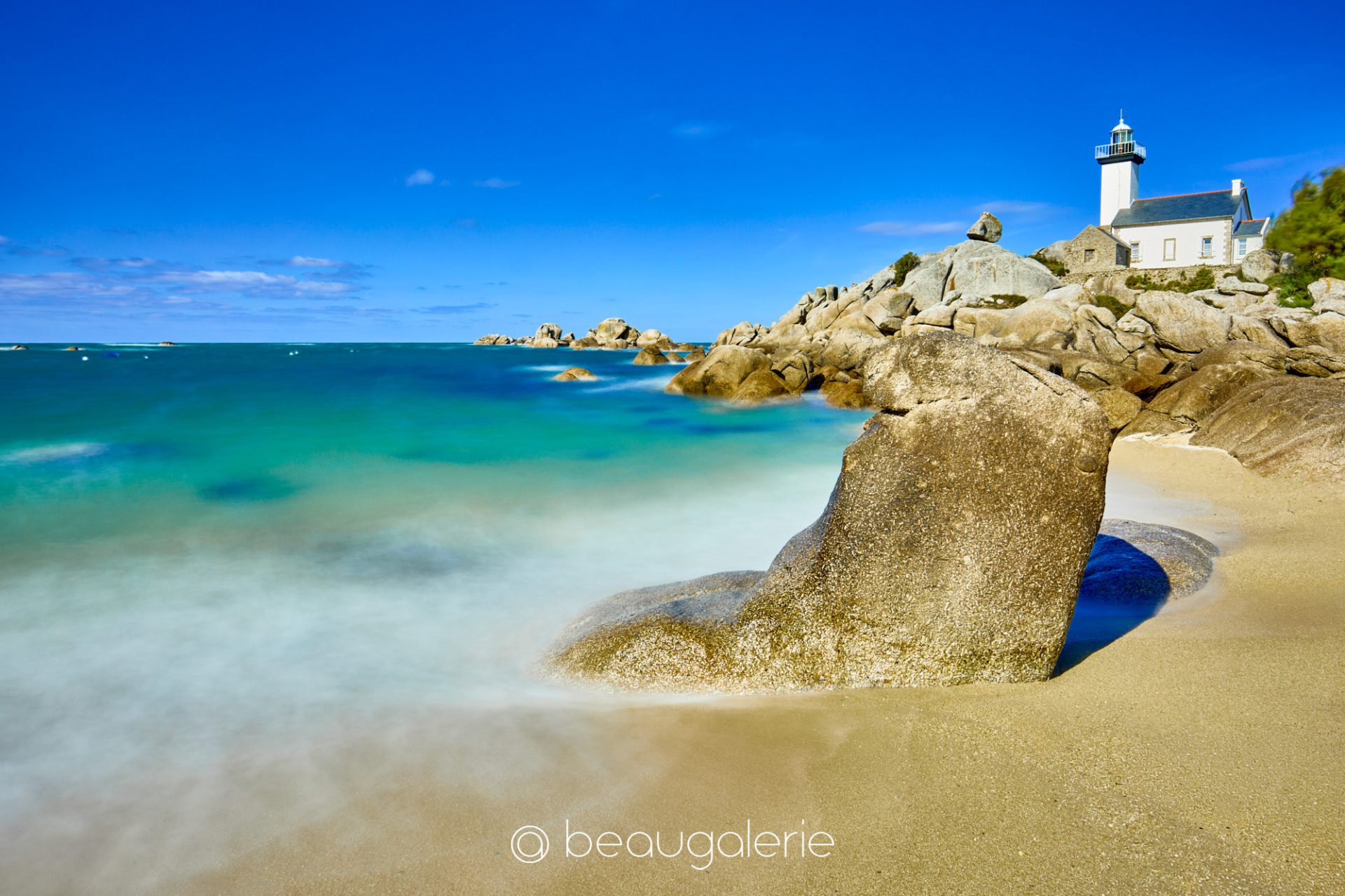 phare-pontusval-eclat-turquoise Phare de Pontusval dominant des rochers de granit et une mer turquoise limpide sous un ciel bleu azur en Bretagne.