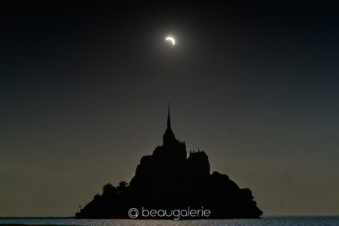 Eclipse solaire baie Mont Saint-Michel, croissant lumineux au-dessus de la silhouette du mont, format standard, photographie d'art