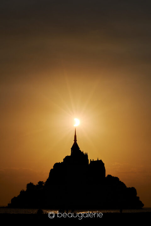 Le ciel d'éclipse au Mont Saint-Michel, halo doré au-dessus de la flèche de l'abbaye, format standard, photographie d'art