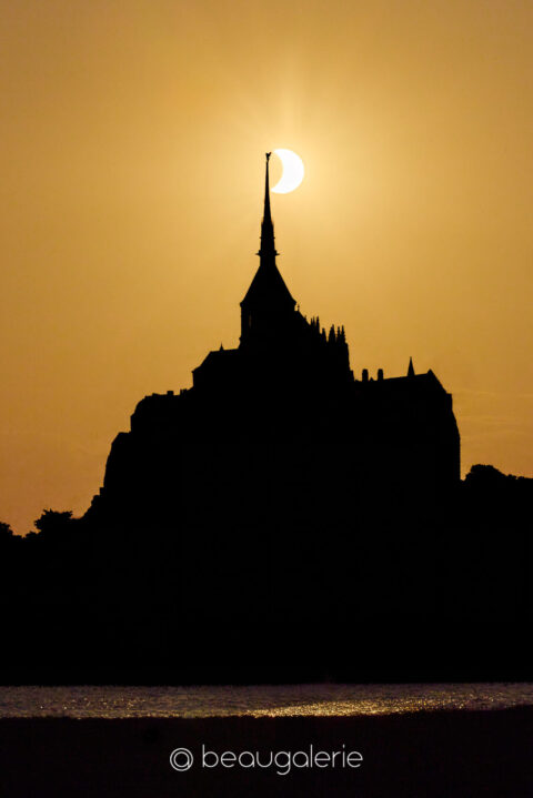 L'éclipse en drapeau sur le Mont Saint-Michel, croissant accroché à la pointe de la flèche, format standard, photographie d'art