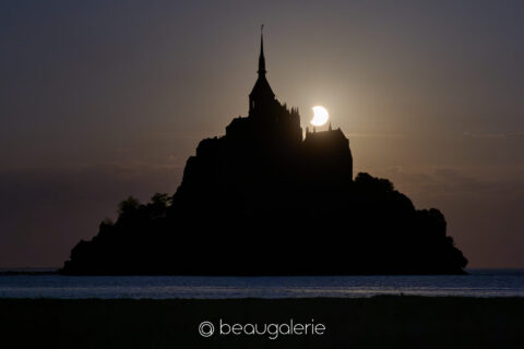La fin de l'éclipse au Mont Saint-Michel, disque solaire partiellement voilé derrière les tourelles de l'abbaye, format standard, photographie d'art