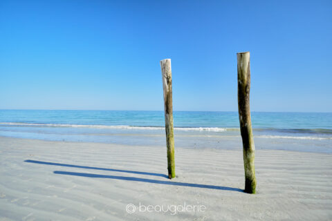 Deux brise-lames de bois face à l’océan sur la plage de Cleut Rouz, photographie minimaliste