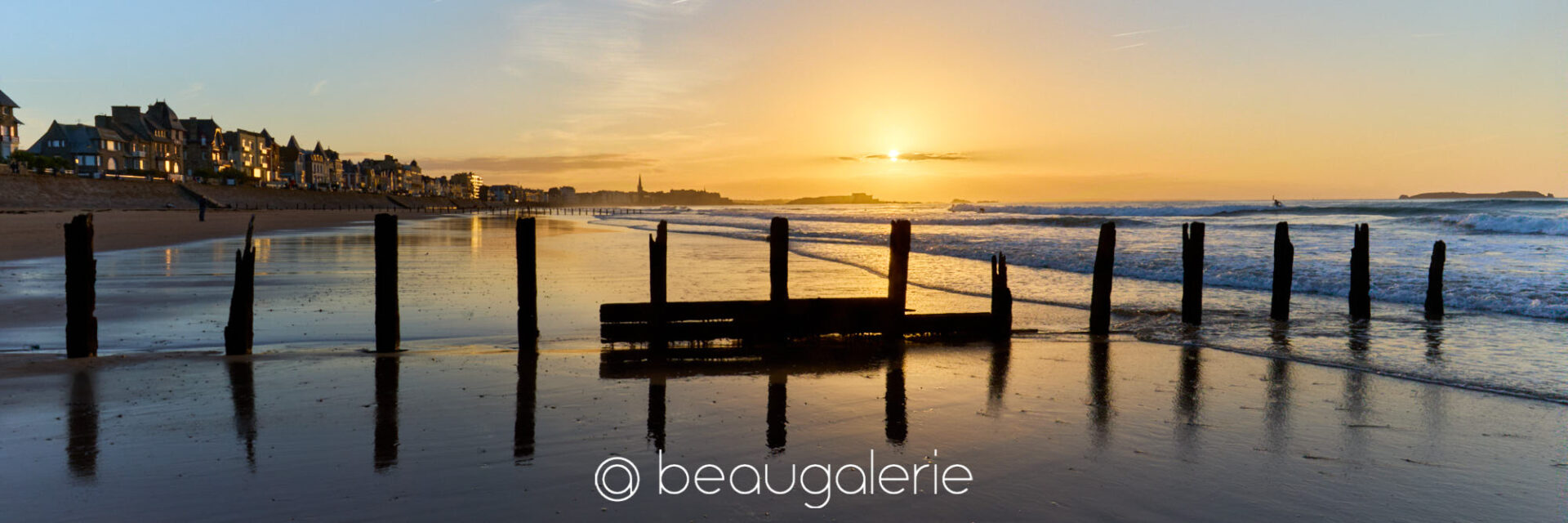 Un coucher de soleil malouin derrière les brise-lames du Sillon Coucher de soleil malouin sur les brise-lames du Sillon en reflet sur le sable mouillé à marée basse, format panoramique, photographie d'art